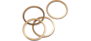 Vier goldfarbene Kupferdichtringe liegen überlappend auf einer weißen Fläche.